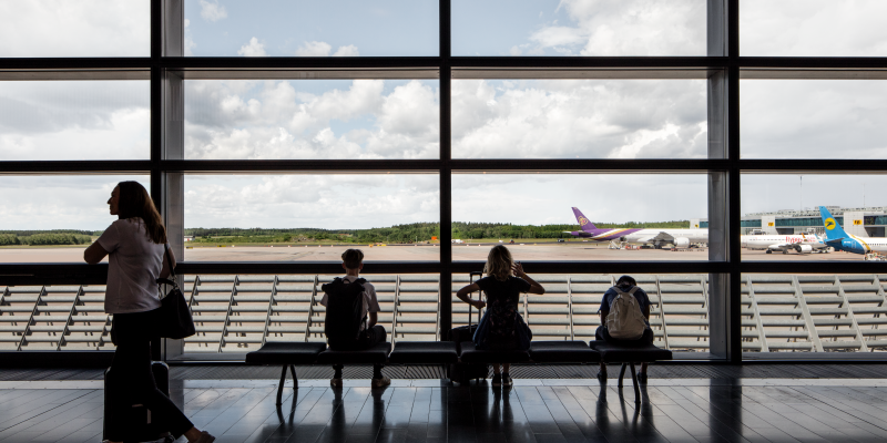 Människor vid ett fönster i SkyCity Arlanda överblickande flygplan på startbana Människor vid ett fönster i SkyCity Arlanda överblickande flygplan på startbana