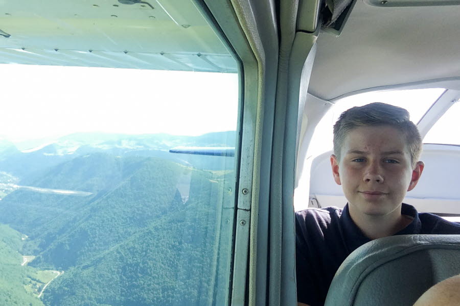 Pojke tittar ut från flygplan på grönklädda berg