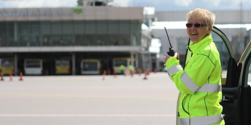 Medarbetare i gul varseljacka med telefon i handen Medarbetare i gul varseljacka med telefon i handen