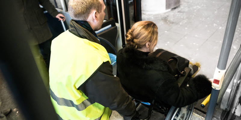 En person med nedsatt rörighet får assistans i rullstol En person med nedsatt rörighet får assistans i rullstol