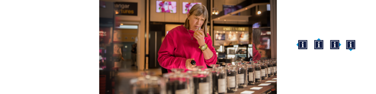 En kvinna i rosa tröja doftar på parfym i en butik En kvinna i rosa tröja doftar på parfym i en butik