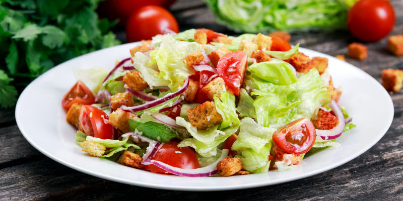 Vit tallrik med sallad och tomater Vit tallrik med sallad och tomater