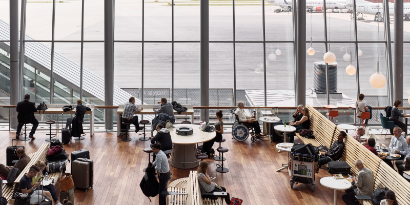 Människor i SkyCity Arlanda vid stort fönster med flygplan utanför Människor i SkyCity Arlanda vid stort fönster med flygplan utanför