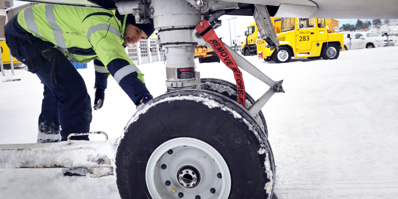 Personal under ett flygplan kollar landningsstället Personal under ett flygplan kollar landningsstället